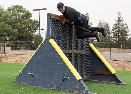Recruit climbing over a wall obstacle